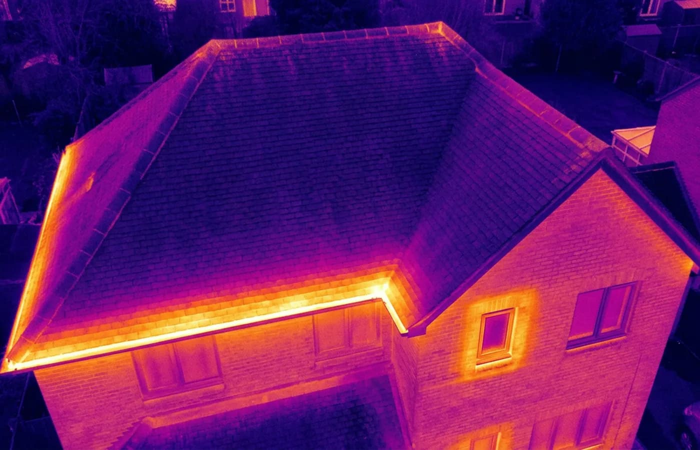 Radiometric thermal image of a house roof and upper elevation in ironbow false colour, with a warm band along the eaves and around a window